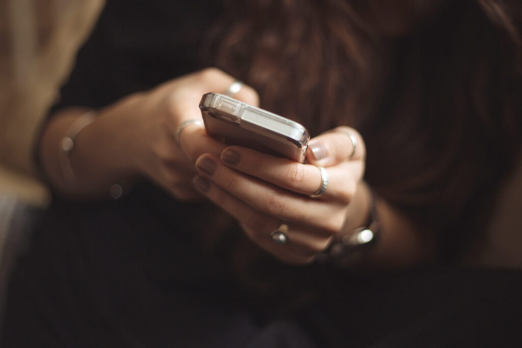 close up photo of woman typing on cell phone